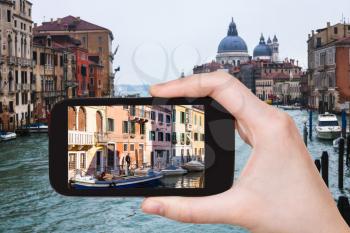 travel concept - tourist photographs palaces on waterfront of Grand Canal in Venice city on smartphone in Italy