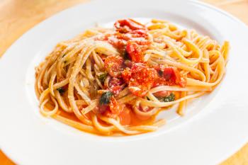 travel to Italy, italian cuisine - spaghetti with spicy tomato sauce on white plate in Sicily