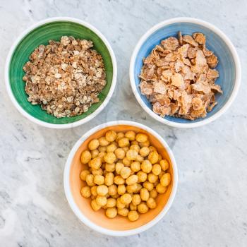 top view of three kind of cold breakfast cereals in bowls on table