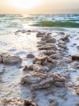 Travel to Middle East country Kingdom of Jordan - crystalline salt on coast of Dead Sea on winter sunset
