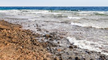 Travel to Middle East country Kingdom of Jordan - oil dirty beach near Aqaba city port on Red Sea in winter