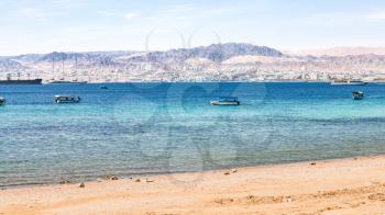 AQABA, JORDAN - FEBRUARY 23, 2012: urban beach of Aqaba and view of Eilat city in the background in winter. Jordan country has only one exit to sea in Gulf of Aqaba, the length of the coast is 27 km