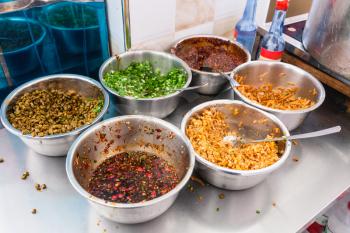 travel to China - bowls with seasonings, spices and toppings on kitchen table in urban chinese eatery in Longsheng town