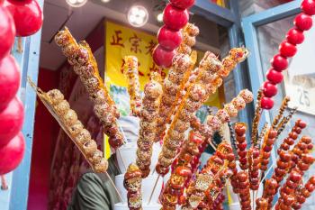 BEIJING, CHINA - MARCH 19, 2017: stall with caramelized fruit on stick on street Qianmen in Beijing city. Qianmen Street runs south from Tiananmen Square, just along the Beijing central axis