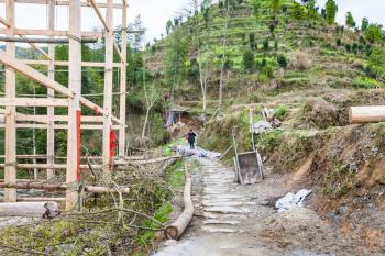 DAZHAI, CHINA - MARCH 25, 2017: peasant near construction site of log house in Dazhai country on Longsheng Rice Terraces. This is central village in famous scenic area of Longji Rice Terraces in Chin