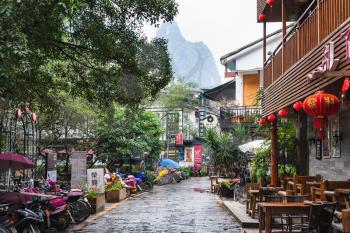 YANGSHUO, CHINA - MARCH 30, 2017: people and cafe on alley in Yangshuo town in spring. Town is resort destination for domestic and foreign tourists because of scenic karst peaks