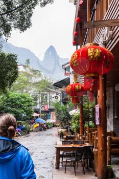 YANGSHUO, CHINA - MARCH 30, 2017: tourists and cafe on alley in Yangshuo town in spring. Town is resort destination for domestic and foreign tourists because of scenic karst peaks