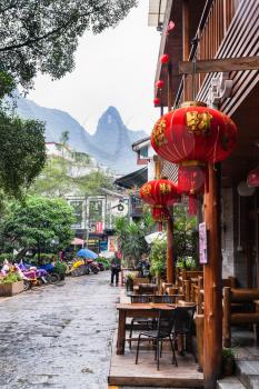 YANGSHUO, CHINA - MARCH 30, 2017: people and eatery on alley in Yangshuo town in spring. Town is resort destination for domestic and foreign tourists because of scenic karst peaks