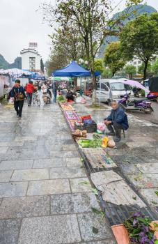 YANGSHUO, CHINA - MARCH 30, 2017: people on outdoor vegetable market on street in Yangshuo in spring. Town is resort destination for domestic and foreign tourists because of scenic karst peaks