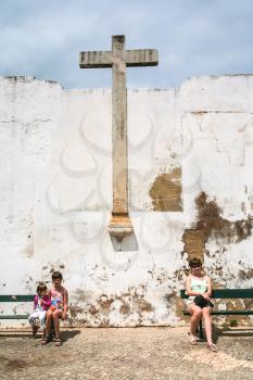 Travel to Algarve Portugal - tourists near old medieval cross in white wall in Faro city