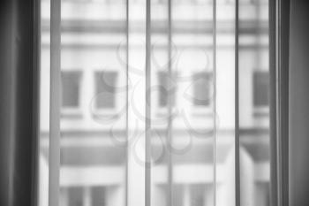 travel to Latvia - transparent curtain from tulle fabric on window and view of defocused apartment house on background in Riga city