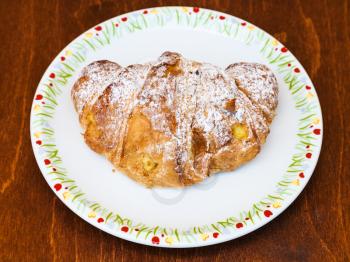 fresh italian croissant filled by vanilla cream on wooden table