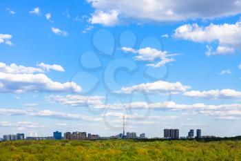 blue sky with white clouds over residential district and green forest of Timiryazevsky park in Moscow city in sunny summer day