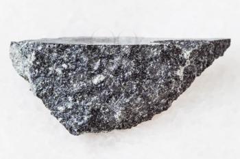 macro shooting of natural mineral rock specimen - piece of dolerite (diabase) stone on white marble background from Raikonkoski district, Karelia, Russia