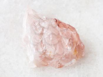 macro shooting of natural mineral rock specimen - raw crystal of rose quartz gemstone on white marble background from Kiv-Guba mine, Karelia, Russia