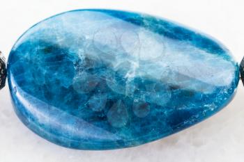 macro shooting of natural mineral rock specimen - cabochon from polished Kyanite gemstone on white marble background