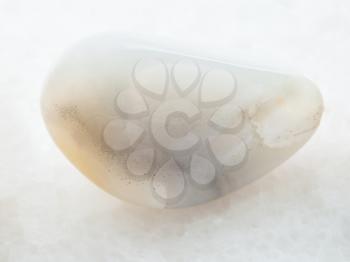 macro shooting of natural mineral rock specimen - tumbled white Agate gemstone on white marble background