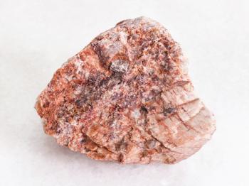 macro shooting of natural mineral rock specimen - rough pink Granite stone on white marble background from Brittany