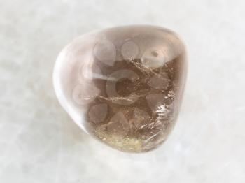 macro shooting of natural mineral rock specimen - polished smoky quartz gem stone on white marble background
