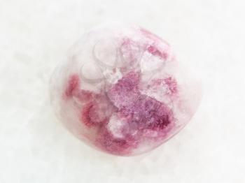 macro shooting of natural mineral rock specimen - polished pink Sodalite gemstone on white marble background from Russia