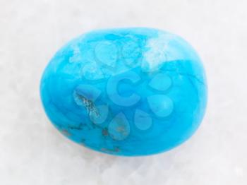 macro shooting of natural mineral rock specimen - polished Turquenite (blue howlite) gem stone on white marble background