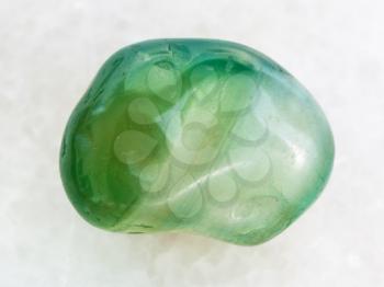 macro shooting of natural mineral rock specimen - polished green dyed agate gemstone on white marble background