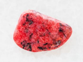 macro shooting of natural mineral rock specimen - tumbled red Agate gemstone on white marble background from Mexico