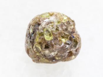 macro shooting of natural mineral rock specimen - tumbled Peridot gemstone on white marble background