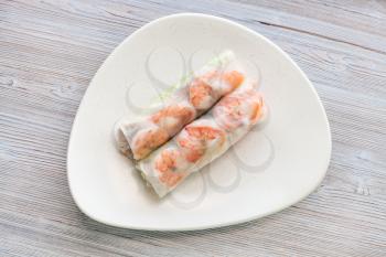 top view of Nem cuon (fresh Vietnamese nem roll with shrimps, mango and ginger) on white plate on wooden table
