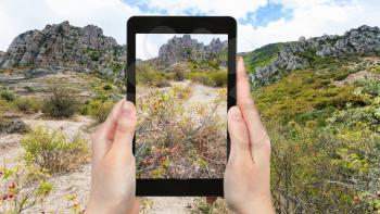 travel concept - tourist photographs Demerdzhi Mountains from The Valley of Ghosts on Crimean Southern Coast inCrimea in september on tablet