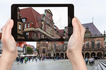 travel concept - tourist photographs old house on Bremer Marktplatz (Bremen Market Square) in Bremen city in Germany in autumn rain on tablet