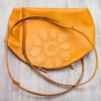 top view of back side of handmade yellow leather bag on wooden table