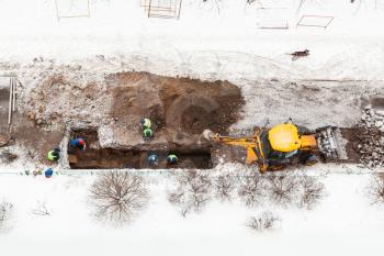 above view of road workers changing pipes in winter in Moscow city