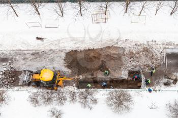 top view of road workers changing sewer pipes in winter in Moscow city