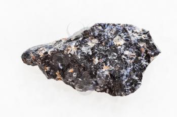 macro shooting of natural mineral rock specimen - rough obsidian (volcanic glass) stone on white marble background