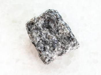 macro shooting of natural mineral rock specimen - rough Gabbro stone on white marble background