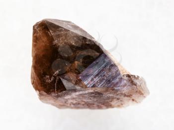 macro shooting of natural mineral rock specimen - raw crystal of smoky quartz gemstone on white marble background