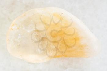 macro shooting of natural mineral rock specimen - polished yellow Citrine gemstone on white marble background