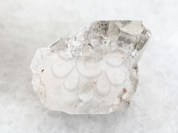 macro shooting of natural mineral rock specimen - rough rock-crystal of quartz gemstone on white marble background