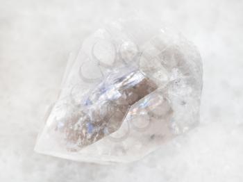 macro shooting of natural mineral rock specimen - raw rock crystal of quartz gemstone on white marble background