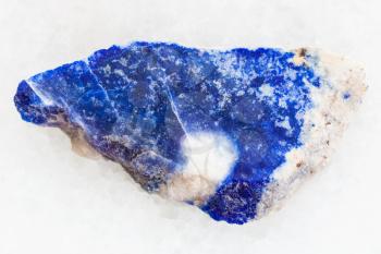 macro shooting of natural mineral rock specimen - rough lazurite (lapis lazuli) stone on white marble background