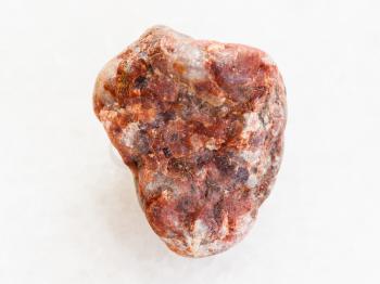 macro shooting of natural mineral rock specimen - pebble of Pegmatite stone on white marble background