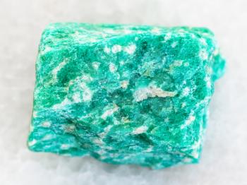 macro shooting of natural mineral rock specimen - raw green amazonite stone on white marble background from Western Keivy, Kola Peninsula, Russia
