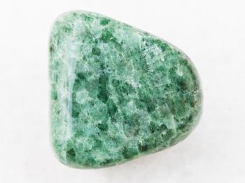 macro shooting of natural mineral rock specimen - tumbled green Jadeite gemstone on white marble background