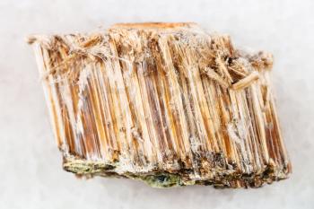 macro shooting of natural mineral rock specimen - rough brown asbestos stone on white marble background from Bazhenovskoye mine in Ural Mountains, Russia