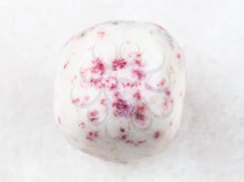 macro shooting of natural mineral rock specimen - cinnabar in tumbled white dolomite stone on white marble background from Peru