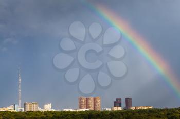 sunbeams and rainbow in rainy sky over Moscow city with TV tower and Timiryazevskiy urban park