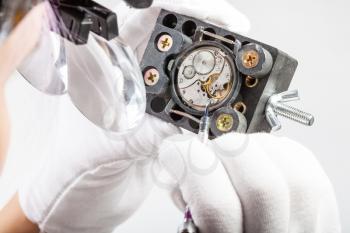 watchmaker workshop - watchmaker in head-mounted magnifying glasses repairs old mechanical watch with screwdriver