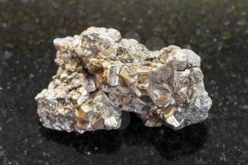 macro shooting of natural mineral rock specimen - rough pyrite stone on dark granite background from Mexico