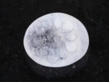 macro shooting of natural mineral rock specimen - polished white agate gemstone on dark granite background